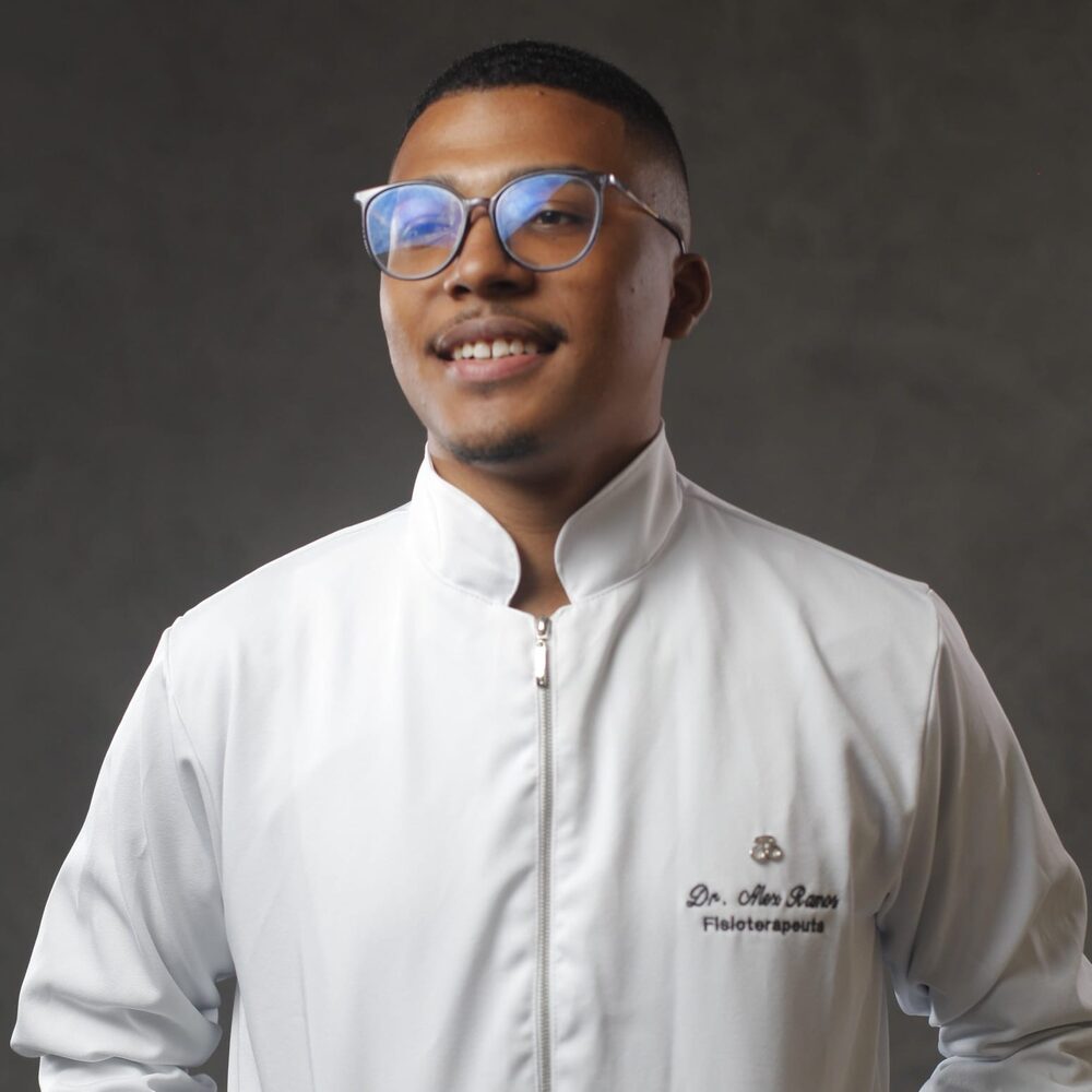 Dr. Alex Ramos, fisioterapeuta, sorrindo, vestindo jaleco branco bordado com seu nome e a especialidade Fisioterapeuta.